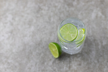 Refreshing drink, water with ice and lime on a gray background.
