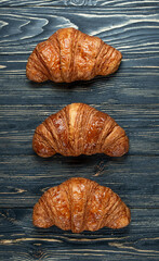 Three croissants french close-up on a black wooden background.