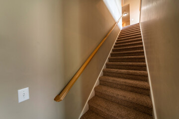 Carpeted basement stairs with wall mounted wooden handrail