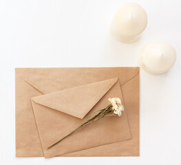 Envelopes, candles and dried flowers on the table, top view