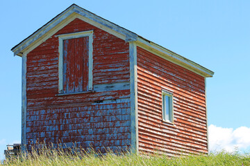 An old red barn on a grassy hill