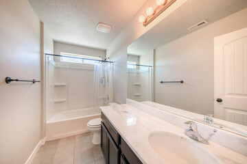 Naklejka na ściany i meble Interior of a white bathroom with black bathroom fixtures and light gray tiles flooring