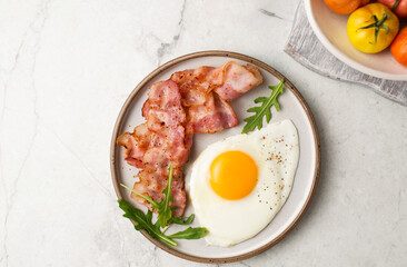 English breakfast. Egg and fried bacon. A cup with tomatoes. Serving breakfast on a marble table. Fried egg.