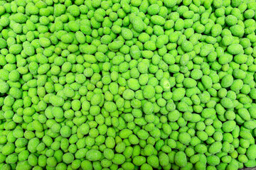 Green salted crunchy peanuts with wasabi. Salted peanuts covered with colored glaze. Delicious appetizer. Food background.