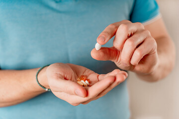 The man holds pills and capsules in his hand. Taking vitamins and medications, close up