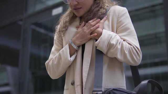 Close-up Of Unhappy Business Woman Touching Chest. Distressed Young Lady Having Panic Attack In City Street. Risk Of Heart Attack Due To Stressful Job And Busy Lifestyle. Health Problem, Medicine