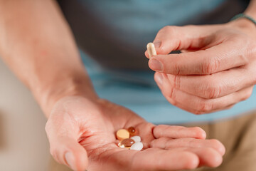 The man holds pills and capsules in his hand. Taking vitamins and medications, close up