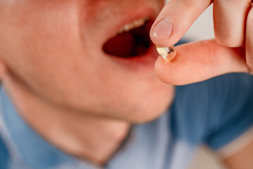 A young  сaucasian man takes a pill. Man making medicine at home, closeup