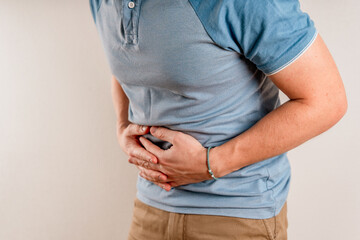 A man is holding on to a sick stomach. The concept of abdominal pain
