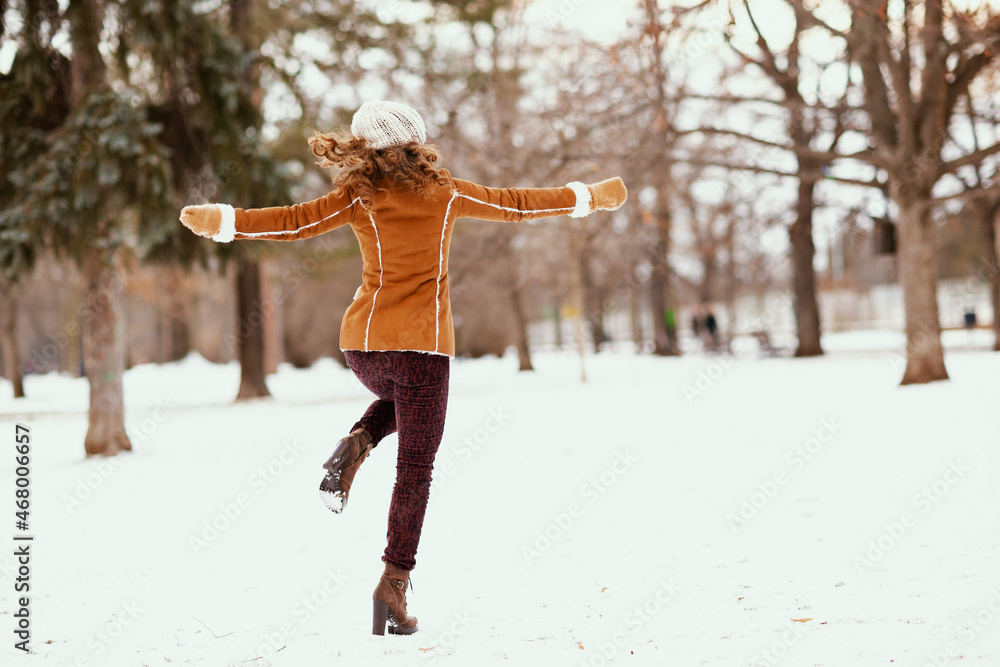 Wall mural seen from behind woman rejoicing outside in city park in winter