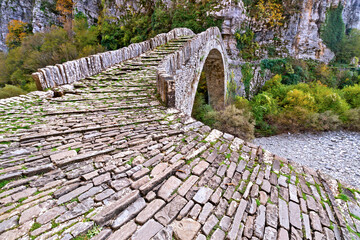 Stone bridge of Kokkoris, one of the famous and beautiful traditional stone bridges in Zagori region, northern Greece, Europe. Most of the bridges were built by local stone masons during the 1900's.  - obrazy, fototapety, plakaty