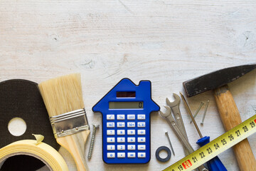 DIY tools and calculator on wooden background, home renovation and construction concept, top view...