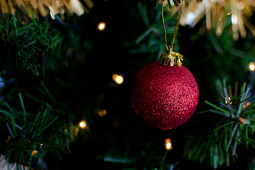 Bola de purpurina roja colgada en el árbol de navidad con bokeh de luces