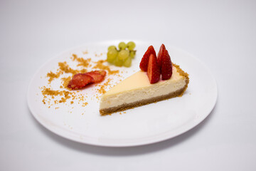 Piece of cheesecake with fresh strawberries on white plate