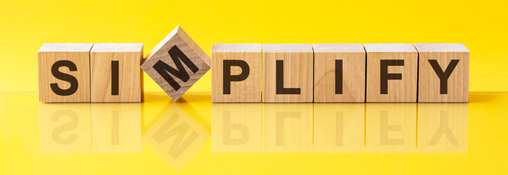 simplify word is made of wooden building blocks lying on the yellow table, concept