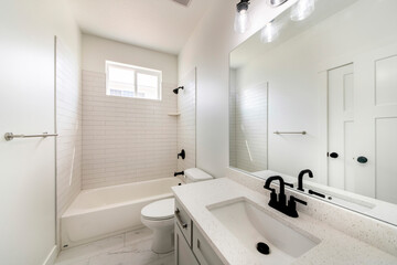 Bathroom with window, white interior, and black fixtures
