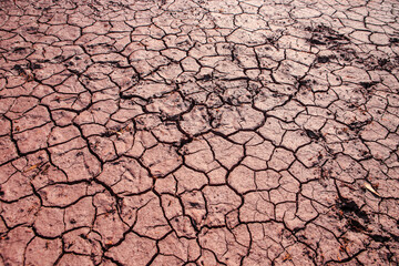 Cracked red earth during drought, the texture of earth during drought. A long time without rain. Infertile soil without plants