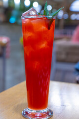 Red drink with ice cubes and green leaf