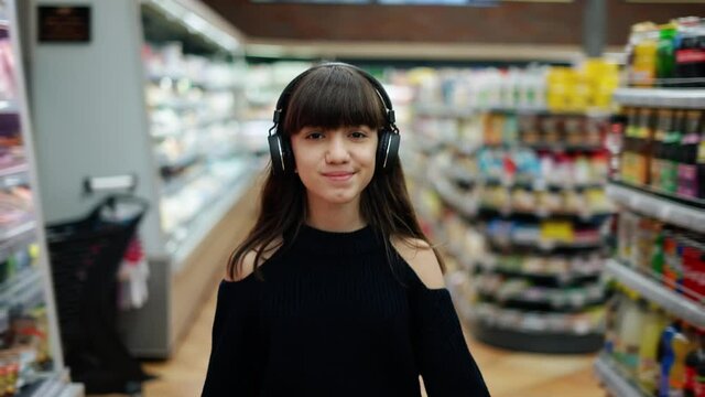 Smiling teenager walking in the supermarket in headphones