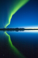 A curtain of Aurora Borealis or Northern Lights reflects in the quiet water of the Kelly River in the Noatak National Preserve, Alaska, USA.
