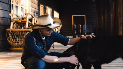 man with cowboy hat petting a dog