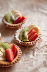 shortbread tartlets with strawberries, kiwi and banana on a craft background