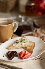 a plate with pieces of chocolate, strawberries and toast on a blurry background