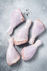 Raw uncooked chicken legs, drumsticks on stone table. Gray background. Top view
