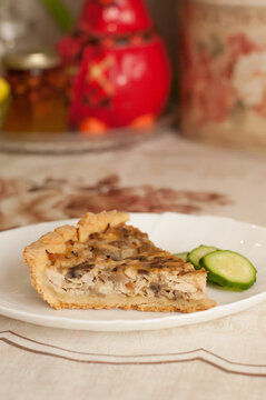 a piece of kish with chicken and mushrooms with cucumber slices on a white plate