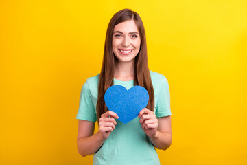 Photo of cute brunette hairdo millennial lady hold heart wear teal t-shirt isolated on yellow color background