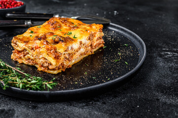 Lasagna with mince beef meat and tomato bolognese sauce on a plate. Black background. Top view....