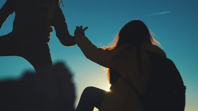help team concept. couple team silhouette of two climber stretching a helping hand to a friend. business teamwork success concept. silhouette sunlight business travel tourists pull a helping hand