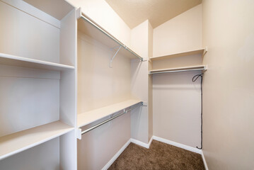 Fototapeta na wymiar Narrow windowless walk-in closet with shelves and metal rods