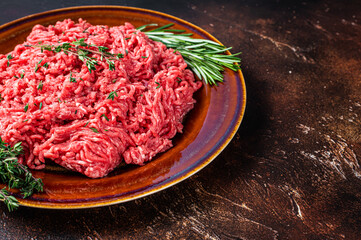 Raw mince beef and lamb meat on a rustic plate with herbs. Dark background. Top view. Copy space