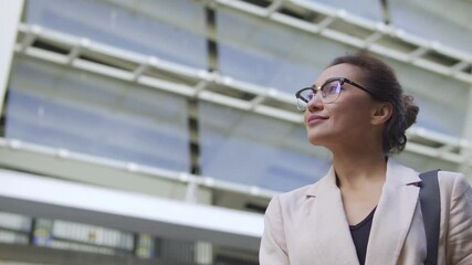 Biracial woman entrepreneur looking at office building, going to rent few floors