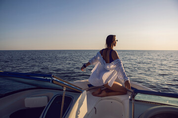 Fototapeta premium young sexy woman in a blue swimsuit and shorts is sitting on bow of a yacht in the summer on vacation