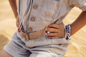 boy is a child traveler in a suit of an archaeologist tracker and wearing hat sitting on the sand in the desert