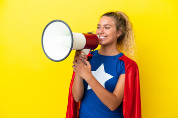 Super Hero woman isolated on yellow background shouting through a megaphone to announce something
