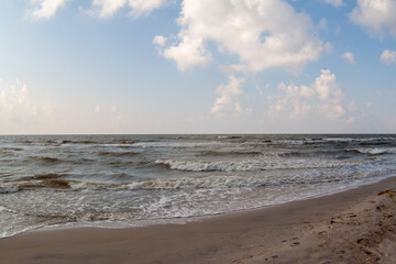 Seascape. Sea Waves rollof the sandy shore. The sky with clouds. Seashore background for a post, screensaver, wallpaper, postcard, poster, banner, cover, title for a website. High quality photography