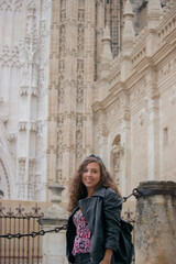 Fototapeta na wymiar Caucasian tourist girl poses smiling towards the camera with Seville cathedral in the background.
