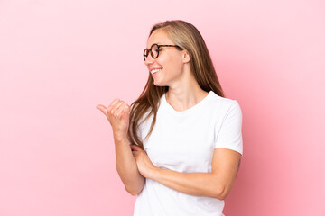 Young English woman isolated on pink background pointing to the side to present a product