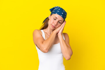 Young English woman isolated on yellow background making sleep gesture in dorable expression
