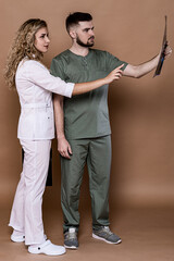 A woman and a man in medical clothing on a caramel background.