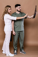 A woman and a man in medical clothing on a caramel background.