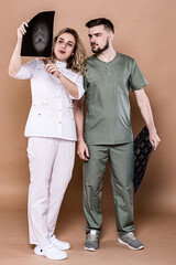 A woman and a man in medical clothing on a caramel background.