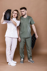 A woman and a man in medical clothing on a caramel background.