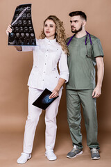 A woman and a man in medical clothing on a caramel background.