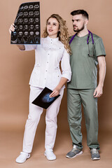 A woman and a man in medical clothing on a caramel background.