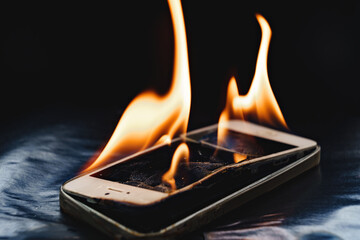 burning broken smartphone on a black background. 