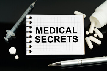 On the black surface are pills, a syringe and a notebook with the inscription - Medical Secrets